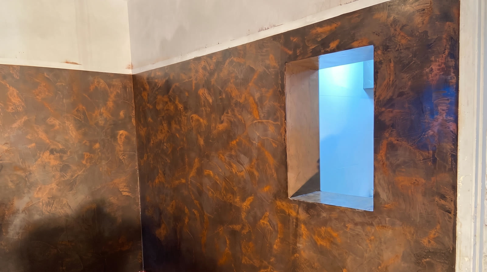 Bathroom wall in rust-coloured polished concrete finish